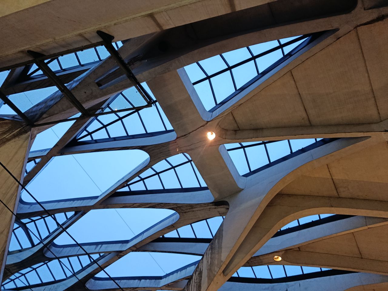 Abstract view of a modern ceiling design featuring concrete beams and skylights.